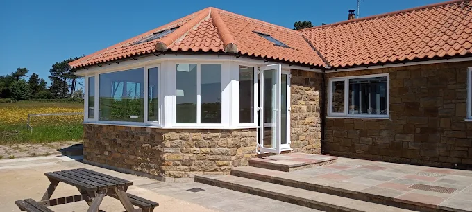 Stone bungalow extension with curved glazing and pantile roof, built by Greener Building in North Yorkshire